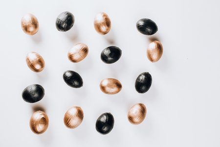 Black and gold decorative wooden eggs over white background. Minimal flat layの写真素材