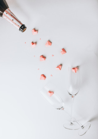 Closeup of a bottle of champagne and a flute filled with pink paper hearts for Valentines Day. On a white background with copy space.の写真素材