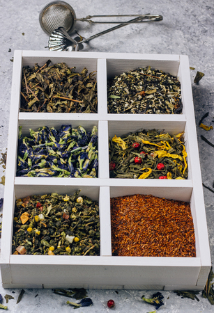 Assortment of dry tea in white wooden box. Tea types backgound: green, black, roybosh, anchan. Top viewの写真素材