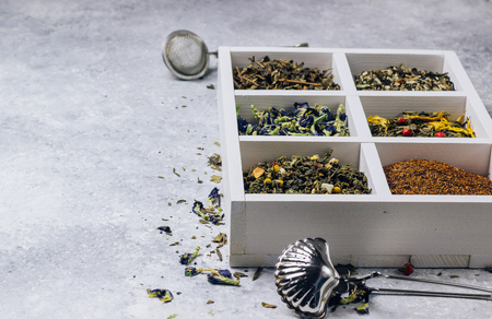 Assortment of dry tea in white wooden box. Tea types backgound: green, black, roybosh, anchan. Top viewの写真素材