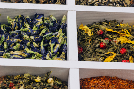 Assortment of dry tea in white wooden box. Tea types backgound: green, black, roybosh, anchan. Top viewの写真素材