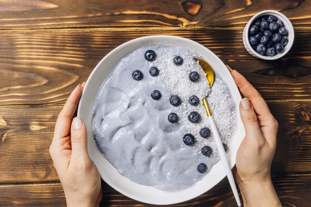 Top view of blue yogurt smoothie bowl made with blueberry, coconut flour on light concreteの写真素材