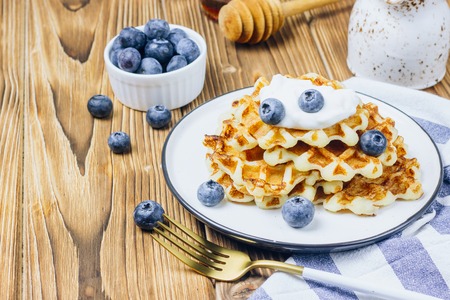 Fresh homemade Belgian waffles with blueberries for breakfast on woodenの写真素材