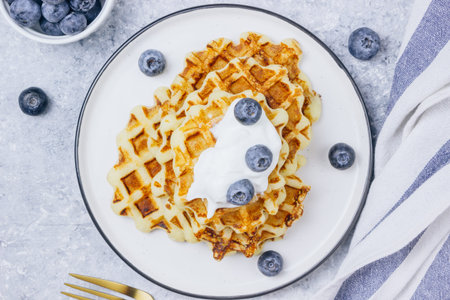 Fresh homemade Belgian waffles with blueberries for breakfast on wooden