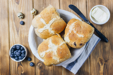 Traditional Easter treats cross buns, served with fresh butter and blueberries on woodenの写真素材