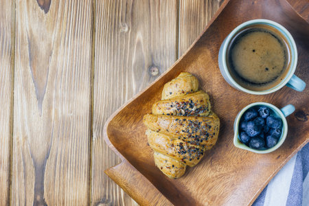 Breakfast served with croissants, coffee, orange juice and berries. on a wooden tray. Top view