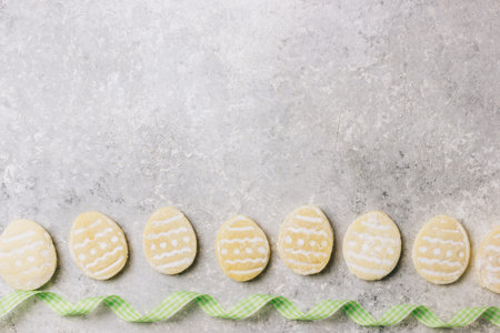 sugar easter cookies with colorful chocolate shape of eggs candy on grey background. Top view