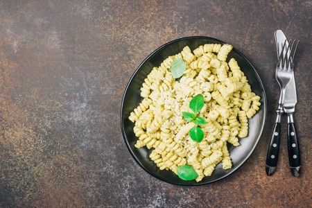 Fusilli pasta with basil, pesto sauce and parmesan cheese on black plate, top view, copy spaceの写真素材