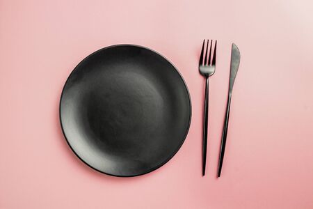 Elegant black and pink table setting: plates, napkin and silverware. Flat lay. Pink backgroundの写真素材