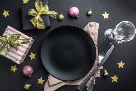 Christmas table setting with black plate, silverware, napkin and decorations over black table. Top view copy space. Christmas backgroundの写真素材