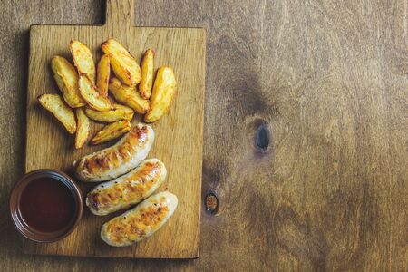 Meal for the Munich Oktoberfest with sausages, potato and pretzels served with beer over rustic wooden backround. Top viewの写真素材