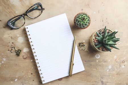 Office desk with hot coffee, plant, eyeglasses on beige stone background. Business desk minimal style concept with copy space. Top view. Flat layの写真素材