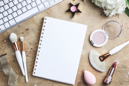 Office table with flowers, make up brush and cosmetics. Womens blog concept. Freelancer. Top view. flat lay.の写真素材