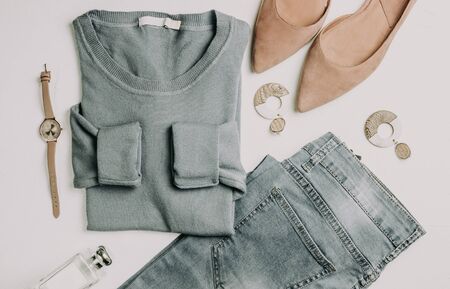 Woman fashion clothes set flatlay. Blue pullover, blue jeans, pink balet shoes, watch, wooden earrings on white background. Flat lay. Top viewの写真素材