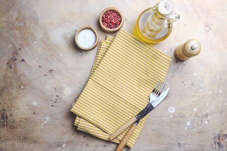 Table setting in yellow warm tones. Yellow cotton napkin, olive oil, salt and pink paper on beige background. Mock up for design. Place for text. Flat layの写真素材
