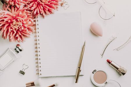 Office desk with pink dahlia flowers, notepad paper blank and women's accessories. Modern minimalist business blog template. Flat lay. Top view. Copy space.の写真素材