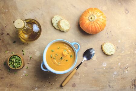 Homemade pumpkin soup and pumpkins on beige rusticの写真素材