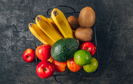 Bananas, apples, kiwi, lime and avocado in black metal basket. Ecological Zero Waste Food Shopping...