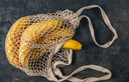 Eco cotton string mesh bag with Bananas. Ecological Zero Waste Food Shopping concept.