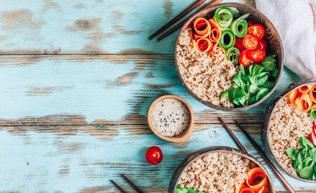 Vegan Buddha bowl. Healthy meal quinoa, tomato, cucumber, carrot, radish, corn salad in coconut bowls on blue rustic background. Top view. Flat layの写真素材
