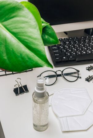 Coronavirus disease COVID-19 prevention set, medical masks KN95 and sanitizer gel for hand hygiene.. Health care concept. Stylish workspace with computer keybord and office supplies. Selective focusの写真素材