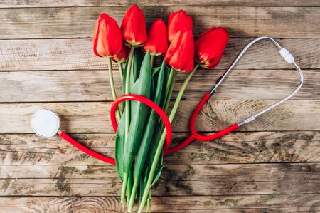 Red tulips and stethoscope on rustic woodenの写真素材