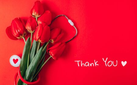 Red tulips and stethoscope on red background. Top view with copy space. Happy Nurse Day. Flat layの写真素材