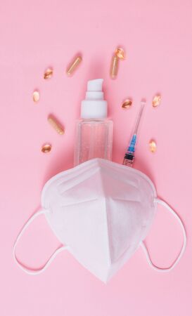 Flat lay of medical mask KN95, syringe, hand sanitizer gel, drops, pills, immunomodulating supplements.の写真素材