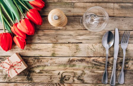 Spring rustic table setting with red tulip, glass and vintage cutlery on the woodenの写真素材