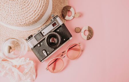 Pink summer female fashion outfit flat lay. Women's straw hat, sunglasses and retro camera. Summer fashion or holiday travel concept. Top view. Flat layの写真素材