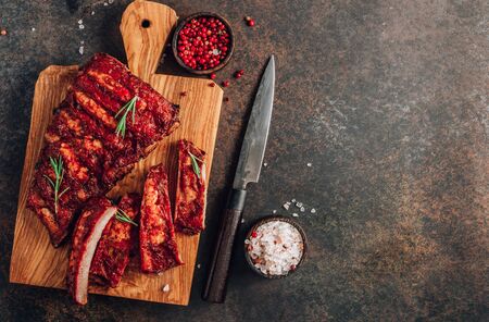 Mexican barbecued ribs seasoned with a spicy tomato sauce served on a wooden chopping board on  darkの写真素材