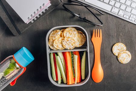Home prepared meal container. Snack Box with cucumber and carrot sticks, healthy rice and corn crackers for work place or schools. Gluten-free diet. Top viewの写真素材
