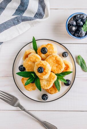 Trandy homemade food - fluffy mini pancakes with blueberries and mint on a white wooden background. Top viewの写真素材