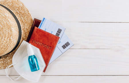 Passport with face mask, sunglasses and hand sanitizer gel on woodenの写真素材