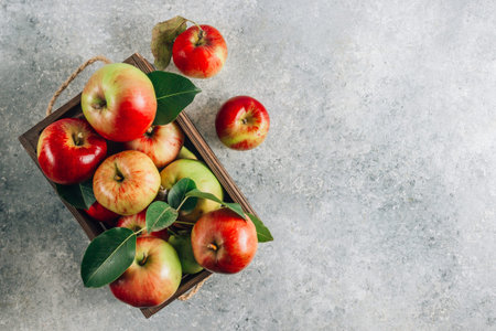 Fresh organic green and red apples in the wooden box. On light gray background.の写真素材