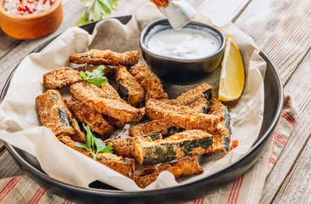 Crispy zucchini sticks with yogurt dip on rustic wooden background. Healthy snackの写真素材