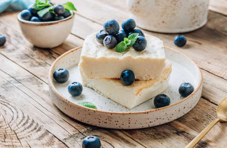 Fresh cottage cheese casserole with blueberries on white plate on rustic wooden background. selective focusの写真素材