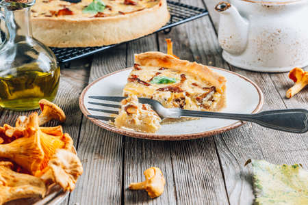 Homemade quiche or tart with chanterelles on rustic wooden background.の写真素材