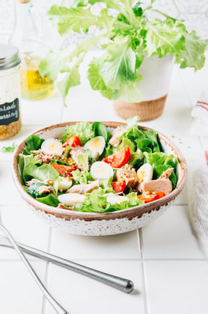 Healhty tuna salad with tomato, quail eggs, lettuce and salad dressing with olive oil, lemon juice and grain mustard.の写真素材