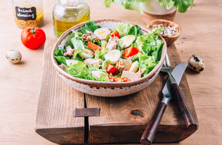 Salad with canned tuna, tomato, quail eggs, lettuce and salad dressing with olive oil, lemon juice and grain mustard.の写真素材