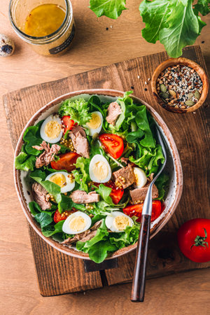 Salad with canned tuna, tomato, quail eggs, lettuce and salad dressing with olive oil, lemon juice and grain mustard.の写真素材