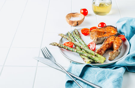 Grilled salmon with asparagus on white tiled background. Mediterranean diet conceptの写真素材