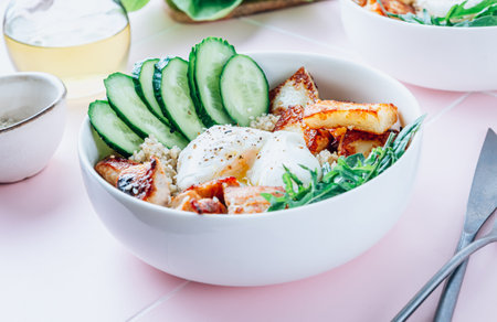 Buddha bowl dish with grilled Halloumi cheese, quinoa, chicken fillet, cucumber, arugula and egg.の写真素材