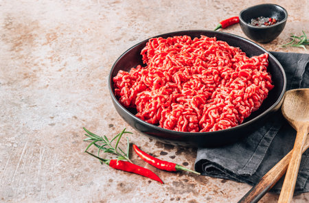 Fresh raw minced beef, ground meat with herbs and spices on black plateの写真素材