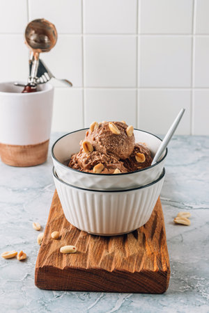 Homemade vegan peanut butter, banana and chocolate ice cream in a bowl with peanuts over gray marble background.の写真素材
