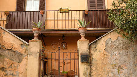 Rome, Testaccio neighborhood. An old style home entrance, with the plants, the iron gate, and a Madonna statue for protection.の写真素材