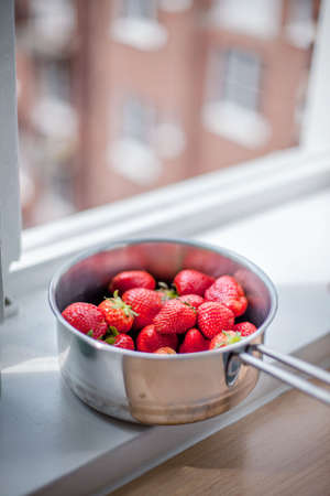 Red strawberries in a pan with a handle top view / fresh summer vitamins to the tableの写真素材
