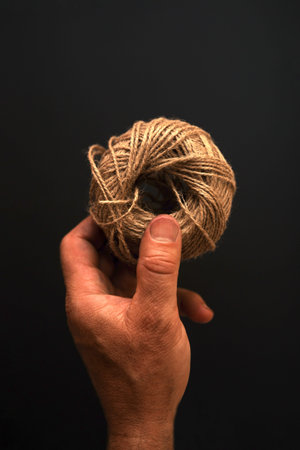 Mans hand holds a spool of thread