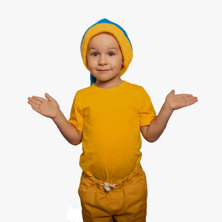 A small cute cheerful boy in yellow clothes spreads his arms to the sidesの写真素材