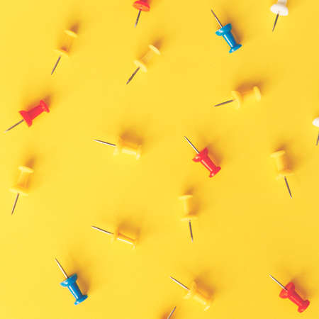 A lot of colorful paper clips lie on an yellow background.の写真素材